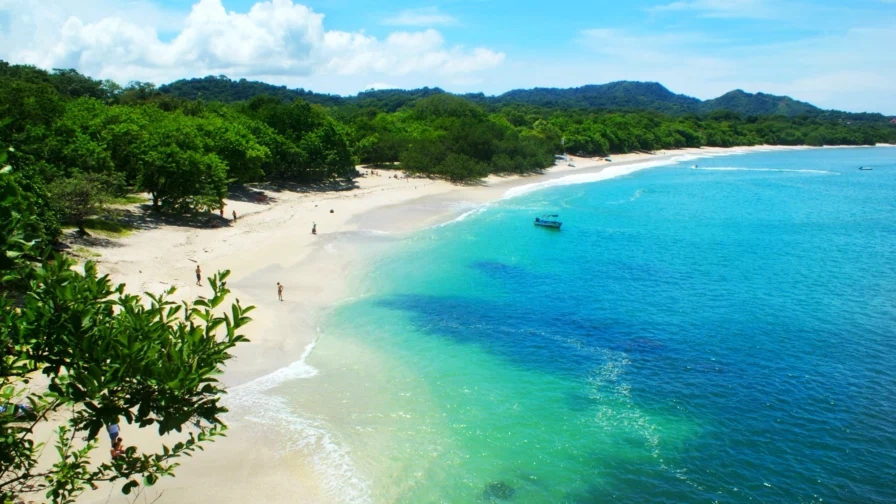 Imagen de Playa Carrillo en Costa Rica en la que aparece una frondosa vegetación, arena blanca y agua en tonos azul intenso y turquesas