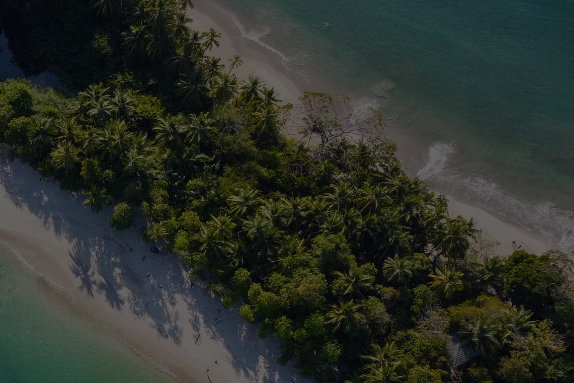 Imagen de un cabo de playa con frondosa vegetación en el centro, playas de arena blanca a sus dos lados y rodeada de aguas turquesas